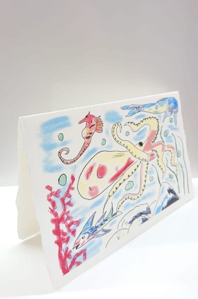 Postcards di Auguri pieghevole in carta di Amalfi. L'illustrazione rappresenta un fondale marino ricco di pesci e di biodiversità.