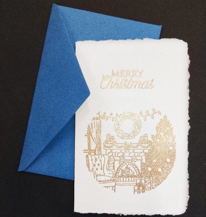 Christmas cards in Amalfi paper made with relief gilding. On the cover an illustration of a lit fireplace with typical Christmas stockings.