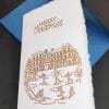 Biglietti pieghevoli in carta di Amalfi per il Natale. I decori sono realizzati con dorature a rilievo realizzate a mano da Lo Scrigno di Santa Chiara. In copertina l'illustrazione di un tipico paesaggio natalizio.