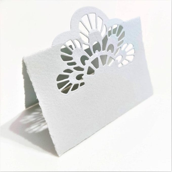 Segna posti per matrimonio in carta di Amalfi colore avorio. Il traforo è ispirato alla coda di pavone. Colore grigio perla